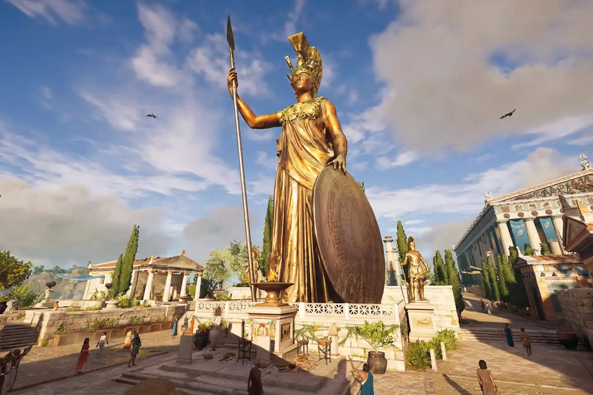 A large bronze statue of the goddess Athena from the multi-platform game Assassin's Creed: Odyssey. The statue wears a golden chest plate and helmet. In one hand she holds a gold tipped spear and in the other balances a circular shield on the ground.