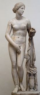Nude statue of the Goddess Aphrodite showing her reaching for her towel while covering her pubic area leaving her breasts exposed.